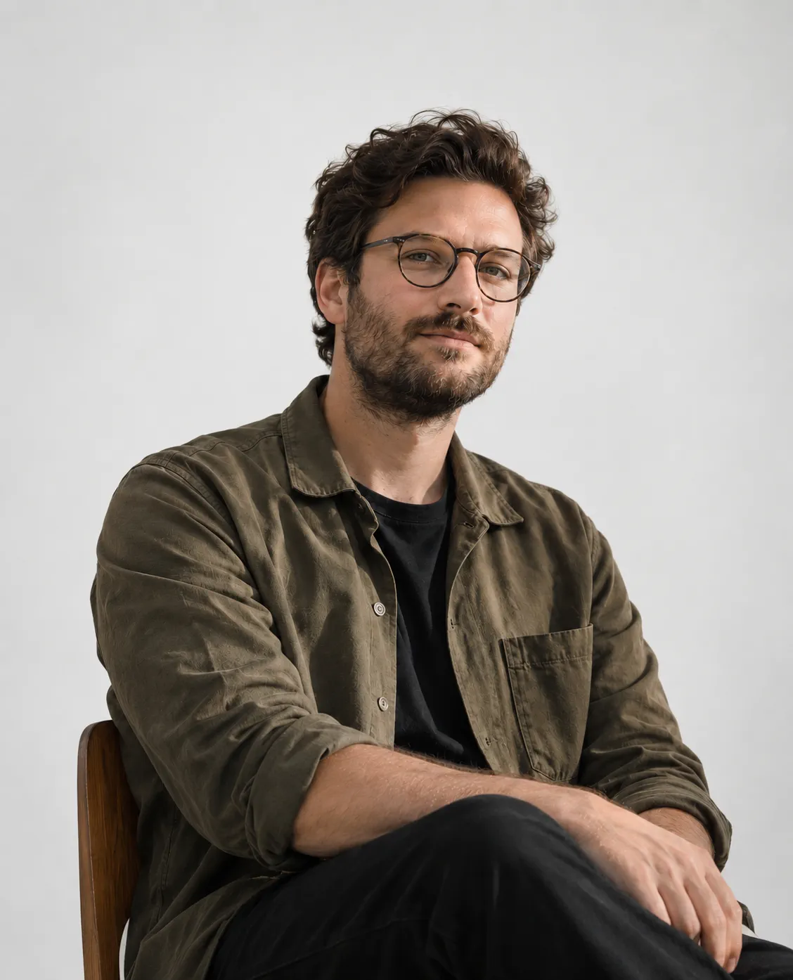 Portrait of Adam Kessler, seated, in an olive shirt and glasses