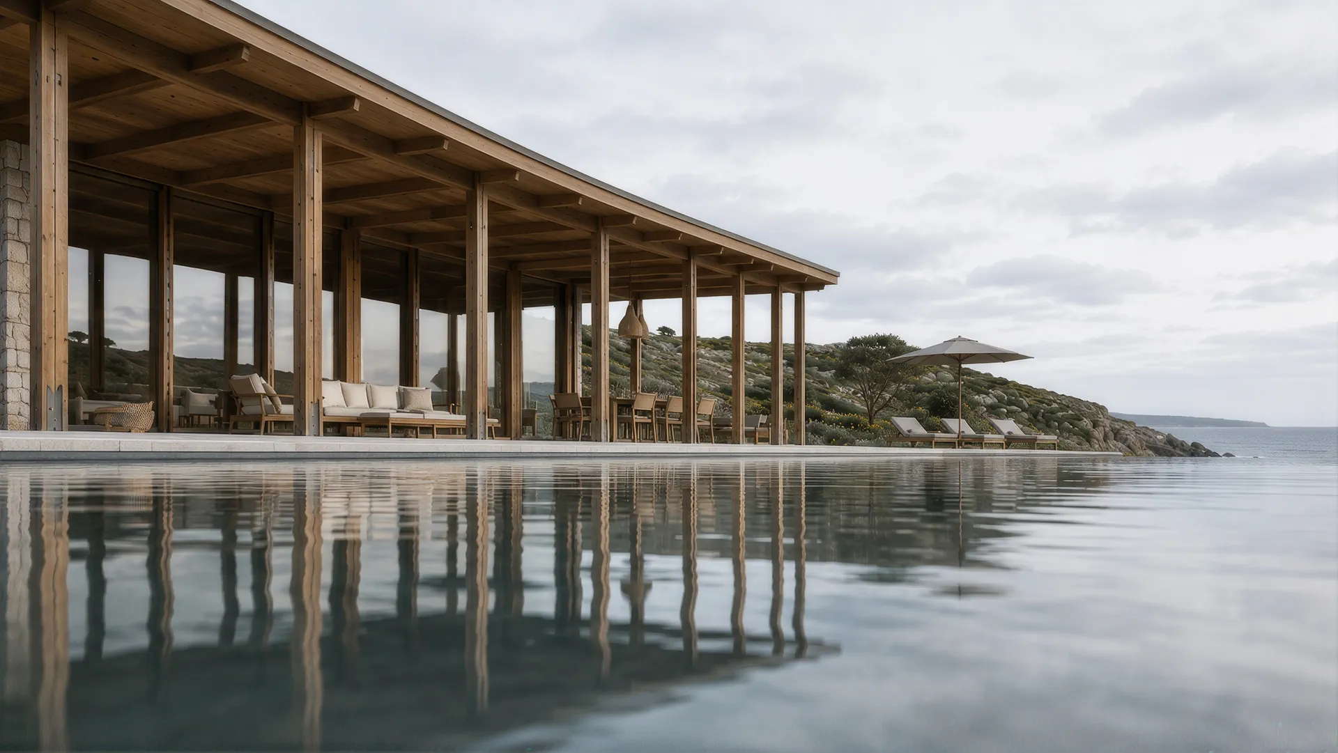 A still infinity pool reflecting the timber colonnade and the coast