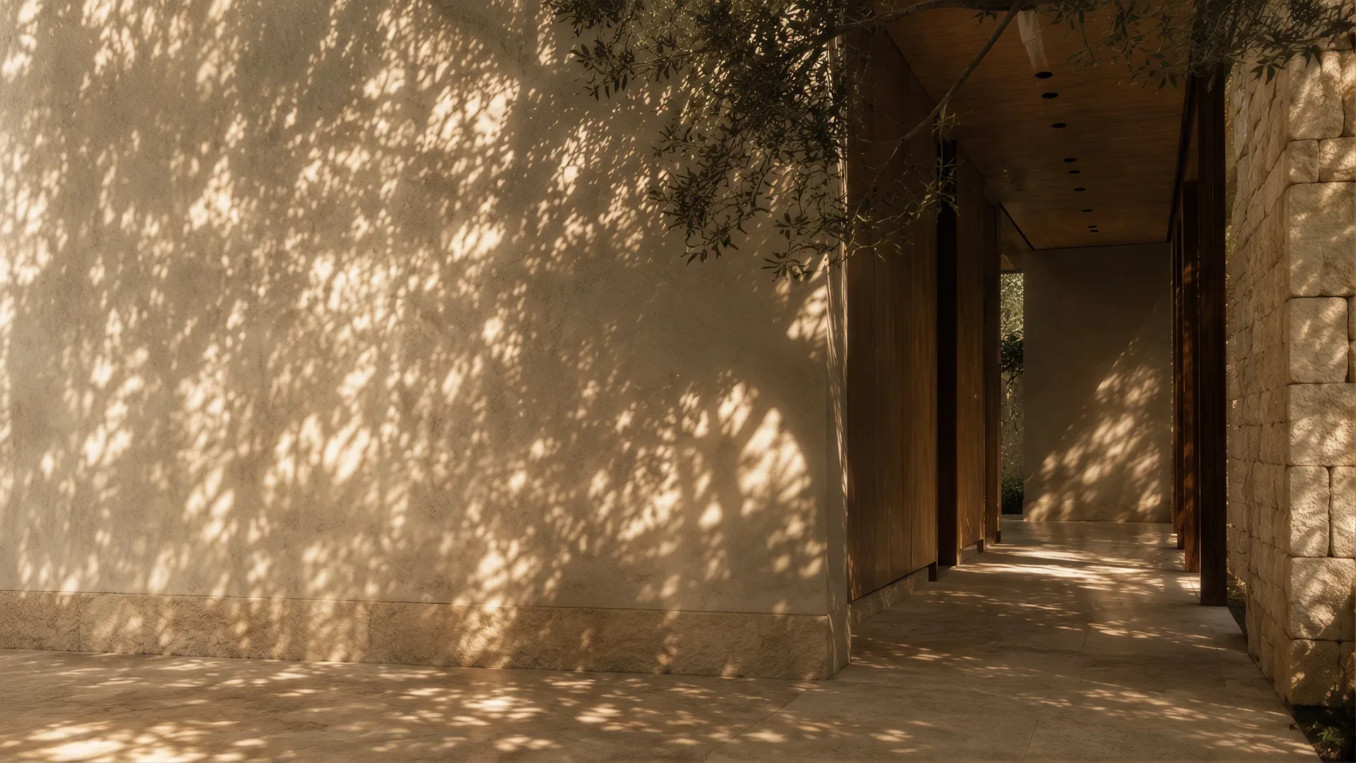 Dappled leaf shadows across a plaster wall and a stone-lined covered walkway